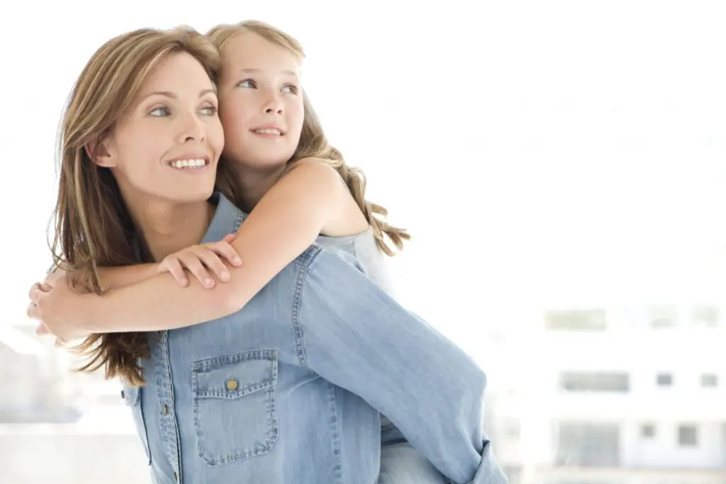 Mother holding daughter on her back.