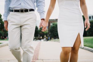 Man and woman wearing form-fitting clothes holding hands
